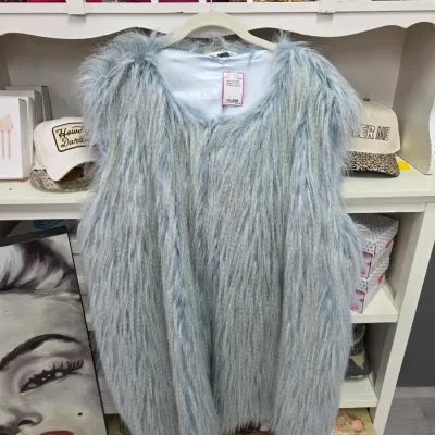 Sale Photo Thumbnail #372: Light blue shag faux fur vest hanging in front of shelving filled with accessories and decor.