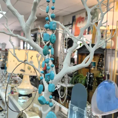 Sale Photo Thumbnail #397: Natural turquoise bead and polished stone necklace displayed on a white tree-style jewelry holder alongside other assorted necklaces.