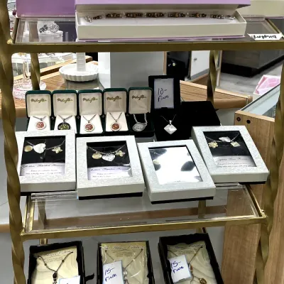 Sale Photo Thumbnail #408: Display shelf filled with boxed sentiment jewelry, including "A Mother's Love Is Forever" beaded necklaces, pendant charm necklaces, and boxed artisan pieces.