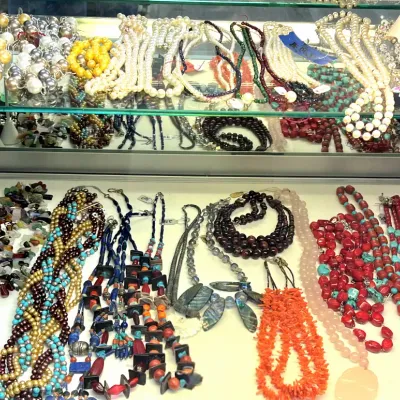 Sale Photo Thumbnail #415: A large collection of vintage beaded and gemstone costume necklaces displayed inside a glass showcase cabinet.