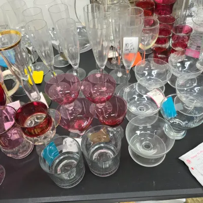 Sale Photo Thumbnail #421: Large collection of assorted glassware, featuring champagne flutes, red-tinted goblets, gold-rimmed stems, and lowball tumblers.