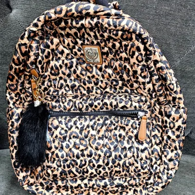 Sale Photo Thumbnail #492: Quilted leopard-print backpack by Juicy Couture featuring tan leather trim and a black faux-fur tassel keychain attached to the front pocket.