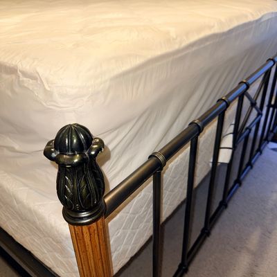 Sale Photo Thumbnail #16: Traditional metal and wood bed frame featuring decorative pineapple finials on fluted wooden corner posts, complete with a mattress and box spring.