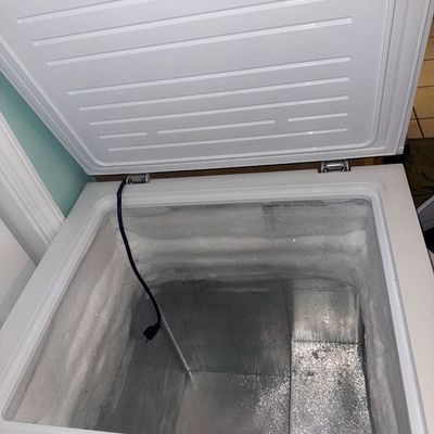 Sale Photo Thumbnail #31: Open white chest freezer showing a metal interior with heavy frost buildup along the top edges.