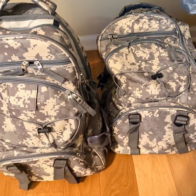 Sale Photo Thumbnail #50: Survival kits in digital camouflage pattern backpacks featuring multiple zippered compartments and front bungee cord ties.