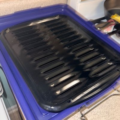 Sale Photo Thumbnail #67: Black porcelain-enamel broiling pan with slatted top insert resting on a purple plastic storage lid.