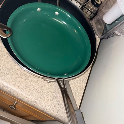 Sale Photo Thumbnail #75: A green non-stick skillet nested inside a larger stainless steel skillet on a speckled kitchen countertop.