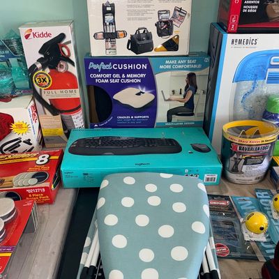 Sale Photo Thumbnail #84: Collection of boxed household items and as-seen-on-TV goods, including a Kidde fire extinguisher, a Logitech wireless keyboard set, a Perfect Cushion seat pad, and a polka-dot tabletop ironing board.