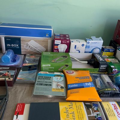 Sale Photo Thumbnail #91: Assortment of modern household supplies, including light bulbs, weatherstripping, vacuum bags, an under-sink mat, and lawn care items in original packaging.