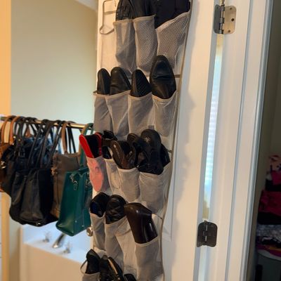 Sale Photo Thumbnail #169: Over-the-door mesh shoe organizer filled with various men's and women's footwear, shown alongside a rack of leather handbags.