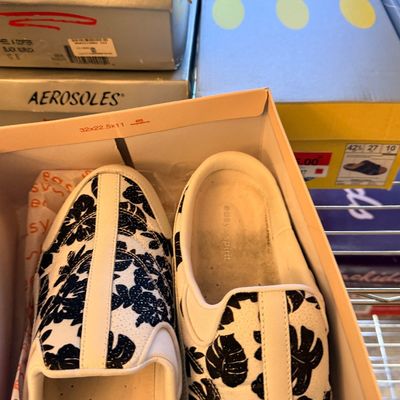Sale Photo Thumbnail #190: Pair of Easy Spirit slip-on shoes with a black and white tropical leaf pattern in their original box, alongside other boxed footwear.