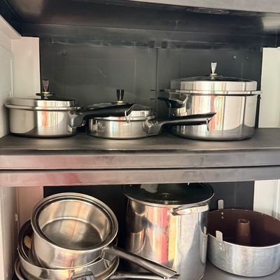 Sale Photo Thumbnail #207: Collection of stainless steel cookware, including pots, pans with lids, a large stockpot, and an angel food cake pan, neatly arranged on shelving units.