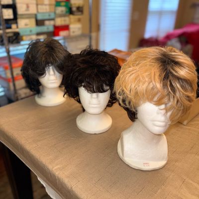 Sale Photo Thumbnail #250: Trio of short synthetic wigs in dark brown, black, and blonde highlights displayed on styrofoam mannequin heads.