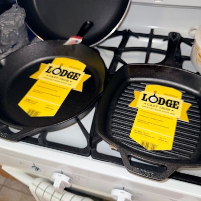 Sale Photo Thumbnail #255: Lodge pre-seasoned cast iron cookware, including a round skillet and a ribbed square grill pan, both appearing unused with original labels attached.