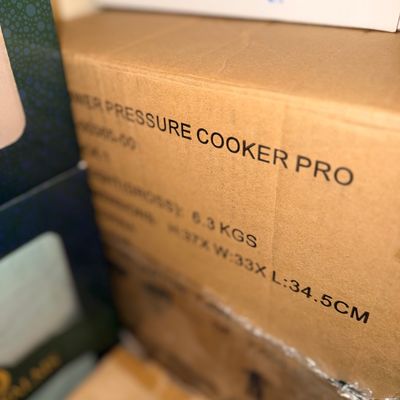 Sale Photo Thumbnail #300: Cardboard shipping box for a Power Pressure Cooker Pro stacked among other retail packaging.