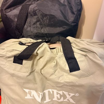 Sale Photo Thumbnail #312: Intex brand inflatable item, likely an air mattress or pool accessory, stored inside its original beige drawstring carrying bag with black handles.
