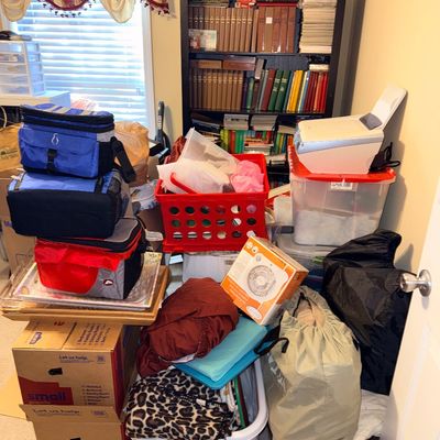 Sale Photo Thumbnail #315: Assorted household items including soft-sided coolers, storage bins, a laundry basket with textiles, and a black bookcase filled with books.