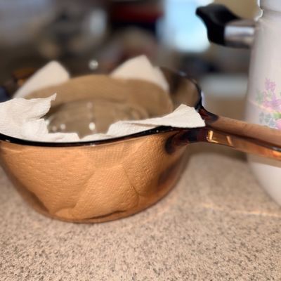 Sale Photo Thumbnail #318: Vintage Vision Corning amber glass saucepan with lid, lined with paper towels for storage protection.