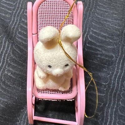 Vintage miniature flocked bunny ornament sitting in a pink metal rocking chair, featuring a gold hanging cord.