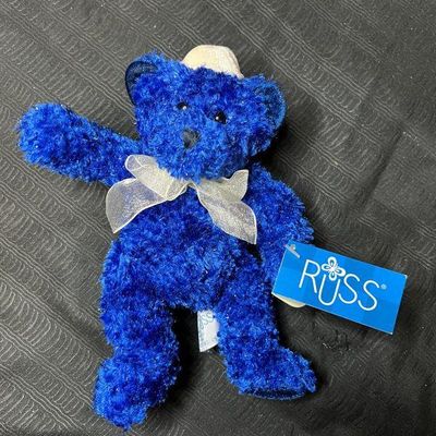 Russ Berrie plush blue teddy bear wearing a white bow and a small hat, complete with original retail tag.