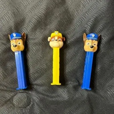 Three Paw Patrol Pez dispensers, featuring two Chase characters on blue stems and one Rubble character on a yellow stem.