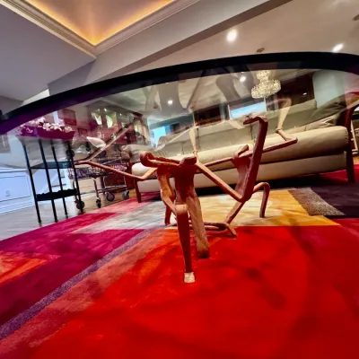 Sale Photo Thumbnail #4: Contemporary glass-top dining table featuring a sculptural figurative bronze or carved wood base depicting intertwined human figures.