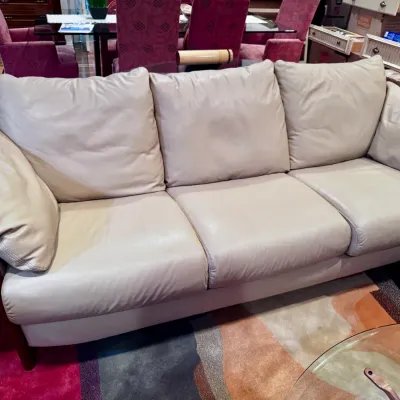 Sale Photo Thumbnail #6: Off-white leather sofa featuring a plush three-cushion design and a exposed cherry-finished wooden frame.