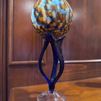 Sale Photo Thumbnail #43: Hand-blown art glass pedestal vase featuring a mottled tortoise and sky blue orb supported by a dark cobalt blue twisted stem on a clear glass base.