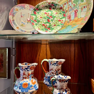 Sale Photo Thumbnail #56: Collection of decorative porcelain including Rose Medallion and floral display plates alongside a three-piece set of Mason's Ironstone pitchers.