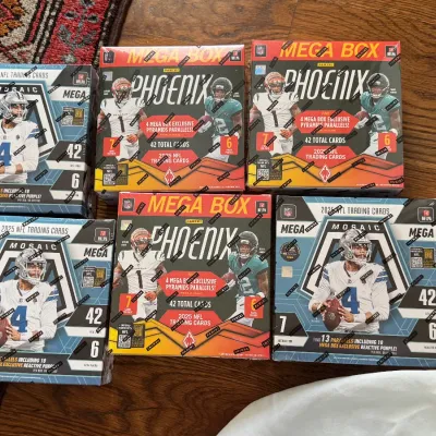 Sale Photo Thumbnail #57: Collection of six unopened 2025 Panini NFL trading card mega boxes, including Mosaic and Phoenix series, in factory-sealed condition.