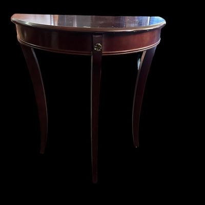 Sale Photo Thumbnail #252: 29"T × 24"W × 12"D Half-moon demilune accent table in rich mahogany finish featuring smooth curved apron  central floral brass medallion detail  and three slender splayed cabriole-style legs. Dimensions: 29" Tall x 24" Wide x 12" Deep.  
