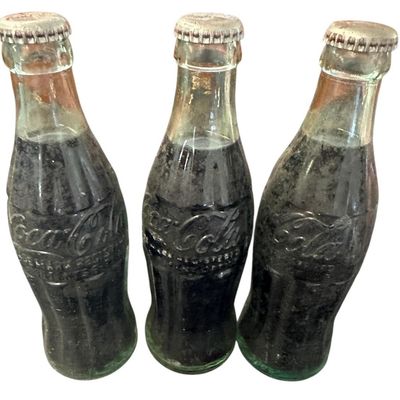 Sale Photo Thumbnail #857:  Three capped / still-full 6.5 oz Coca-Cola bottles. Two Monroe  one Shreveport. Do not wash. Collectible  not for drinking.