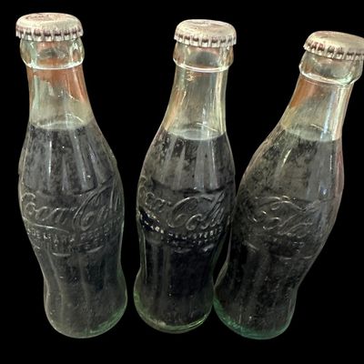 Sale Photo Thumbnail #854:  Three capped / still-full 6.5 oz Coca-Cola bottles. Two Monroe  one Shreveport. Do not wash. Collectible  not for drinking.