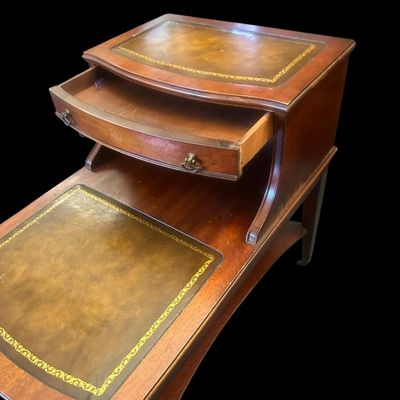 Sale Photo Thumbnail #963: 24.00 x 19.00 x 26.00 Classic 2-tier step-down end table featuring gold-tooled leather inlays on both upper and lower surface tiers  top drawer with brass ring pulls  and lower curved open shelf base.  