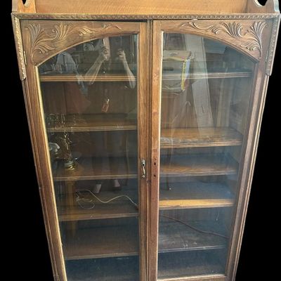 Sale Photo Thumbnail #1063: 70 X 41 X 11 Antique Oak Carved 2-Door Glass Bookcase / Display Cabinet  features solid oak construction  carved floral spandrels above double full-length glass doors  upper gallery backsplash  and multi-tier adjustable interior shelving. (70" H x 41" W x