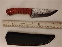 Custom Damascus steel hunting knife featuring a textured reddish-brown wooden handle, shown with its black leather sheath and a ruler for...
