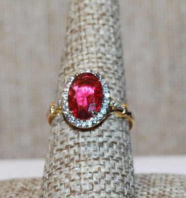 Size 8¼ Light Red Oval Cut Transparent Stone Ring with Full Clear Stones Surround and Side Accents on a Gold Tone Band (3.3g)