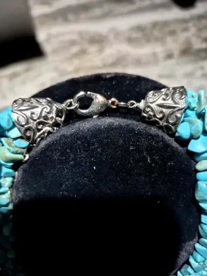Sale Photo Thumbnail #8: This Navajo 6 strand Turquoise Necklace features a stunning array of 7mm tumbled turquoise beads in a beautiful 13 inch strand. The necklace is accented with a steel bell gather, adding a unique touch to the traditional Navajo design. Crafted with silver 