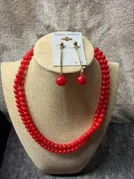 Vintage-style red beaded double-strand necklace paired with matching red drop earrings on a card, displayed on a jewelry bust.