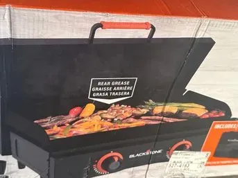 Blackstone tabletop griddle in its original packaging, featuring a rear grease management system and two control knobs.