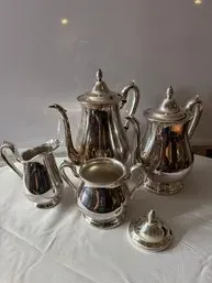 Vintage silver-plated tea and coffee service set, including a coffee pot, teapot, creamer, and sugar bowl with lid.