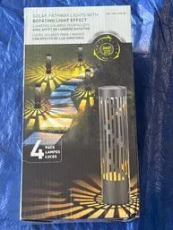 Four-pack of solar pathway lights with rotating light effect, new in original box.