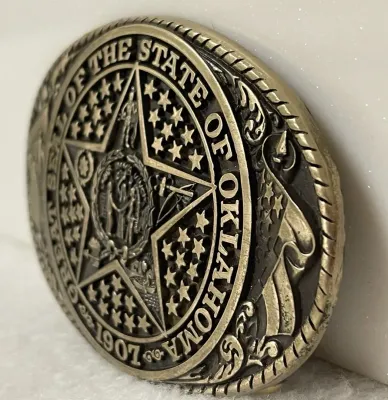 Sale Photo Thumbnail #157: Vintage Tony Lama Great Seal of the State of Oklahoma solid brass belt buckle from the State Series, featuring Oklahoma’s official state seal with the 1907 statehood date and detailed Western imagery throughout.