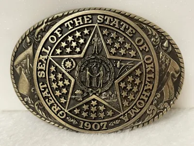 Sale Photo Thumbnail #158: Vintage Tony Lama Great Seal of the State of Oklahoma solid brass belt buckle from the State Series, featuring Oklahoma’s official state seal with the 1907 statehood date and detailed Western imagery throughout.
