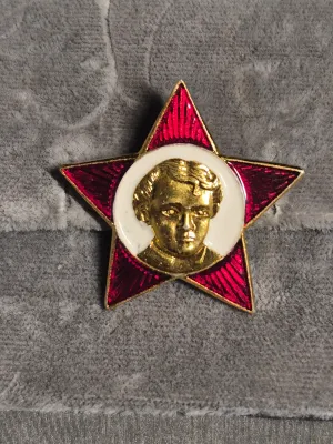Sale Photo Thumbnail #263: A collection of three vintage Soviet-era Russian enamel pin badges. Includes a red star Little Octoberist badge featuring a young Vladimir Lenin, a red flag commemorative badge marked '1870-1990' with Lenin's profile, and a Peterhof 1705 imperial-style sh