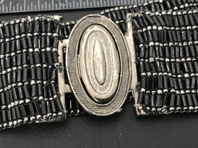 Sale Photo Thumbnail #17: Vintage wide beaded belt featuring black bugle beads and silver-tone seed beads arranged in a textured grid pattern. Features an oval silver-tone slide or hook buckle. Good vintage condition with light wear consistent with age.