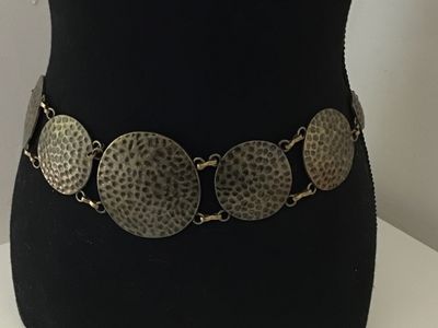 Sale Photo Thumbnail #22: Boho style chain belt featuring linked, hammered circular metal discs in a antique brass/bronze tone finish. Includes an adjustable tail chain with a clasp closure. Shows light vintage wear consistent with age, overall good condition.