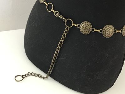 Sale Photo Thumbnail #20: Boho style chain belt featuring linked, hammered circular metal discs in a antique brass/bronze tone finish. Includes an adjustable tail chain with a clasp closure. Shows light vintage wear consistent with age, overall good condition.