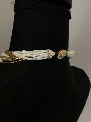 Sale Photo Thumbnail #45: Multi-strand twisted torsade necklace featuring alternating strands of white seed beads and metallic gold-tone glass bugle beads. It features decorative white molded end caps and a gold-tone push-in box clasp with a sunburst pattern. In good vintage condi