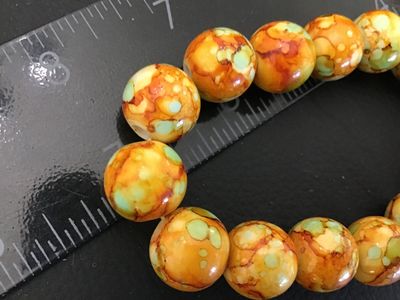 Sale Photo Thumbnail #47: Beaded stretch bracelet featuring round beads in mottled, marbled shades of orange, yellow, and mint green. Each bead measures approximately 8mm to 10mm in diameter. Shows light wear and is in good pre-owned condition.